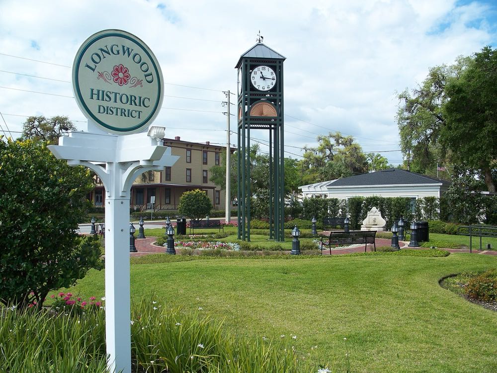 The Longwood Historic District sign and clock tower in a small park, with the Longwood Hotel behind